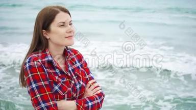 女人看着<strong>海滩</strong>上的海浪。 女旅行者在<strong>暴风雨</strong>天气的<strong>海滩</strong>度假时很冷